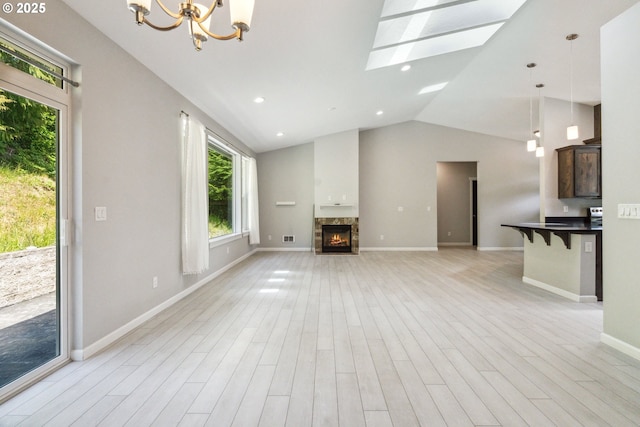 unfurnished living room with light wood-style flooring, a lit fireplace, a chandelier, baseboards, and recessed lighting