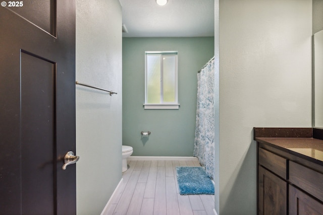 full bath featuring toilet, vanity, baseboards, and wood finished floors