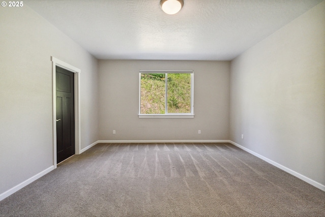 carpeted empty room featuring baseboards