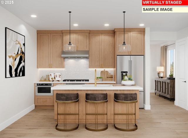 6496 NW Olympic Ln Unit L 25, Camas, WA 98607 - kitchen featuring under cabinet range hood, light countertops, stainless steel appliances, backsplash, and light wood-type flooring
