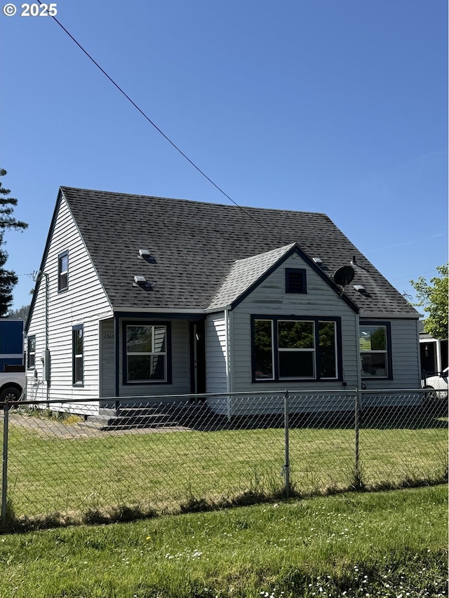 view of front of home featuring fence, a shingled roof, and a front yard