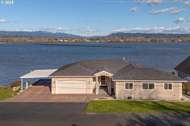 ranch-style home featuring driveway, a front yard, a garage, a water and mountain view, and a carport