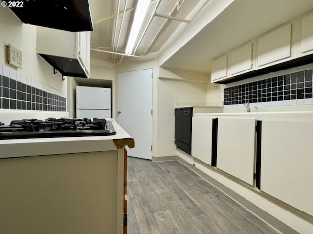 kitchen featuring extractor fan, white cabinetry, light hardwood / wood-style flooring, decorative backsplash, and black appliances