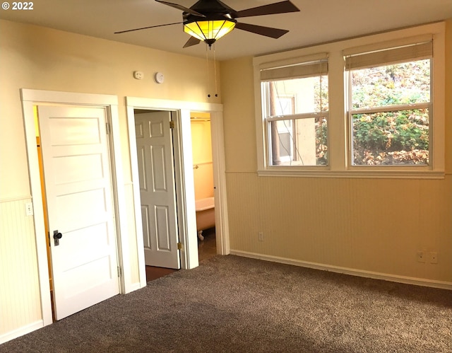 unfurnished bedroom featuring ceiling fan and dark colored carpet