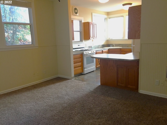 kitchen featuring sink, a healthy amount of sunlight, white gas stove, and kitchen peninsula