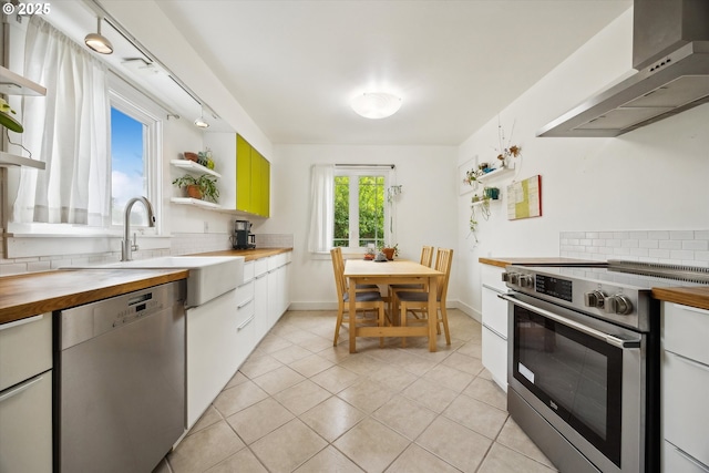 kitchen with stainless steel appliances, wooden counters, ventilation hood, open shelves, and tasteful backsplash
