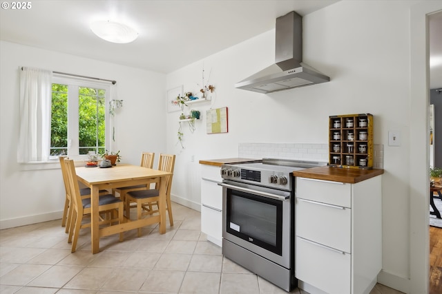 kitchen with stainless steel range with electric stovetop, wall chimney exhaust hood, butcher block countertops, backsplash, and white cabinets