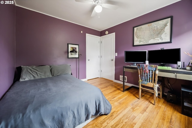 bedroom with wood finished floors, a desk, baseboards, ornamental molding, and a ceiling fan