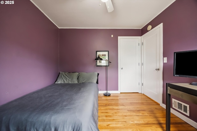 bedroom featuring ornamental molding, wood finished floors, baseboards, and a ceiling fan