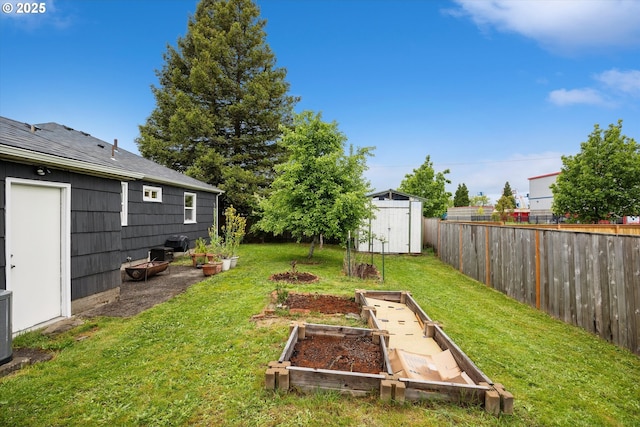 view of yard with a vegetable garden, a storage shed, and an outbuilding