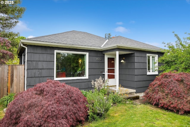 ranch-style home with fence and roof with shingles