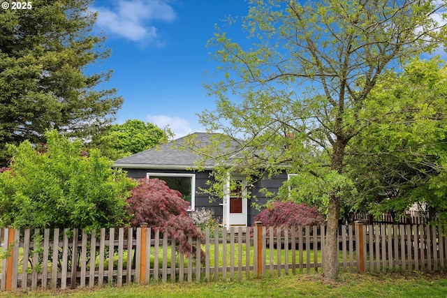 view of property hidden behind natural elements featuring a shingled roof