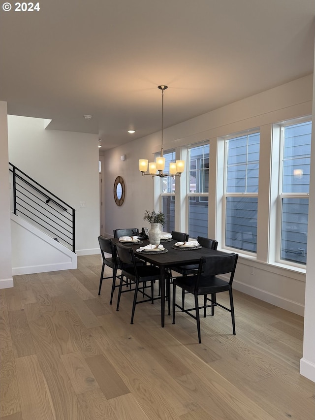 dining area featuring baseboards, stairway, light wood-style floors, and a notable chandelier