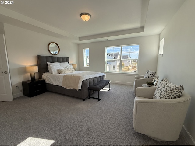 carpeted bedroom with a tray ceiling and baseboards