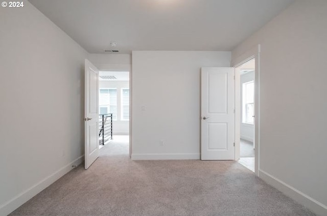 unfurnished room with baseboards and light colored carpet