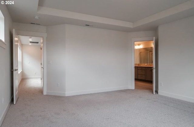 empty room with light carpet, baseboards, visible vents, and a tray ceiling