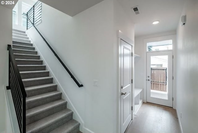 stairs with visible vents and wood finished floors