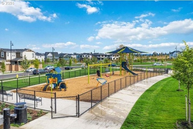 community play area featuring a residential view, fence, and a lawn