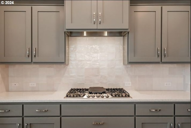 kitchen with backsplash, gray cabinets, stainless steel gas cooktop, and wall chimney range hood