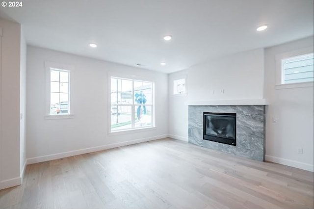 unfurnished living room featuring baseboards, wood finished floors, recessed lighting, and a premium fireplace