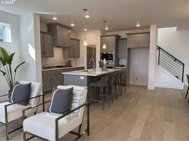 kitchen featuring gray cabinets, light wood-style flooring, a sink, and stainless steel appliances