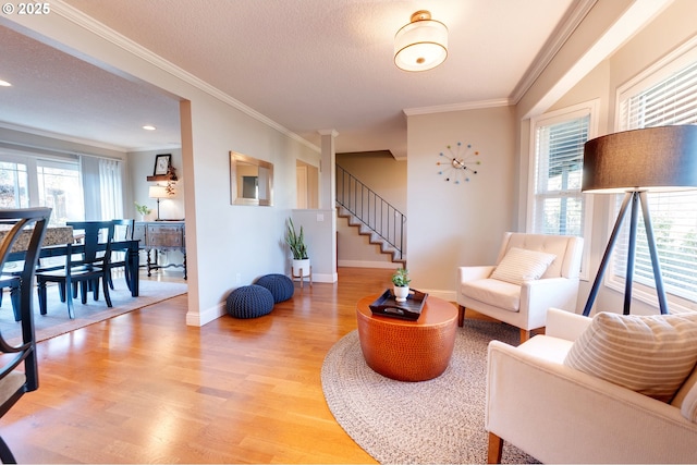 living area with ornamental molding, light wood-type flooring, and a textured ceiling