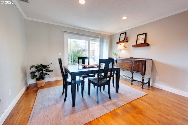 dining room with hardwood / wood-style floors, crown molding, and a textured ceiling