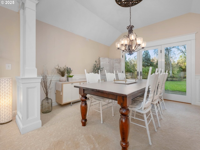 dining area featuring ornate columns, light carpet, a chandelier, and vaulted ceiling