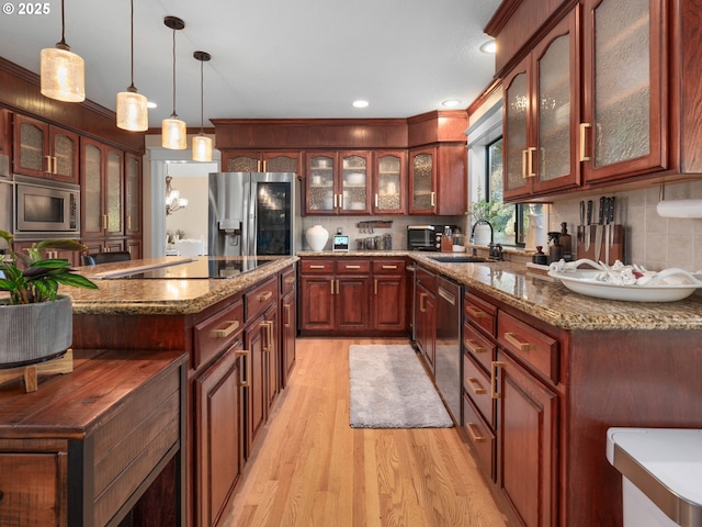 kitchen with sink, hanging light fixtures, tasteful backsplash, light hardwood / wood-style floors, and appliances with stainless steel finishes