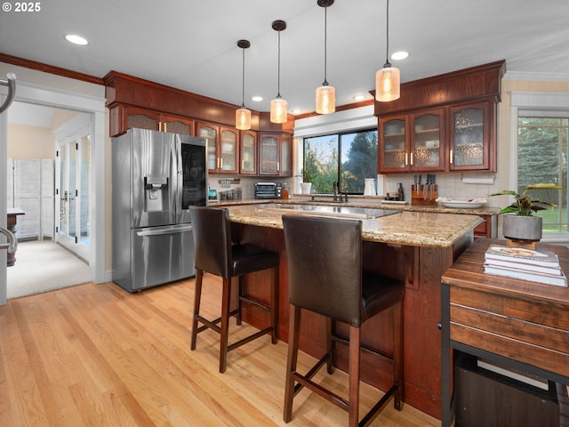 kitchen featuring pendant lighting, backsplash, light hardwood / wood-style flooring, stainless steel fridge, and a kitchen island