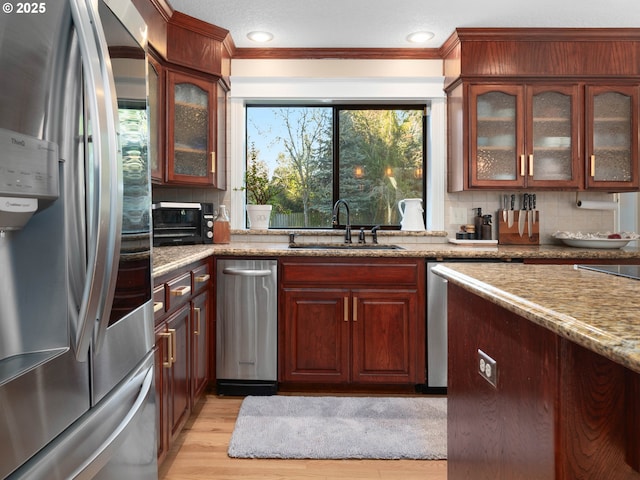 kitchen featuring sink, light hardwood / wood-style flooring, light stone countertops, tasteful backsplash, and stainless steel refrigerator