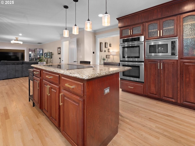 kitchen featuring a center island with sink, crown molding, hanging light fixtures, light stone countertops, and stainless steel appliances