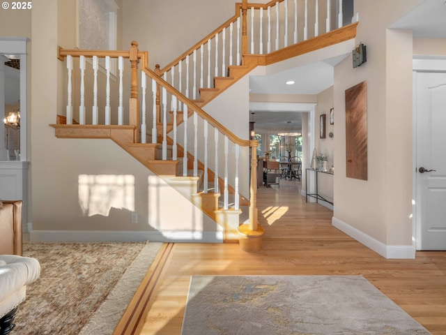 entrance foyer with a towering ceiling, light hardwood / wood-style floors, and a notable chandelier