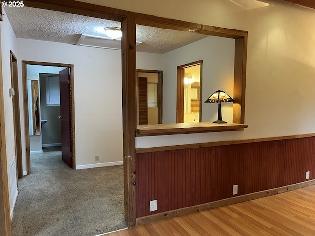 hall featuring carpet flooring and a textured ceiling