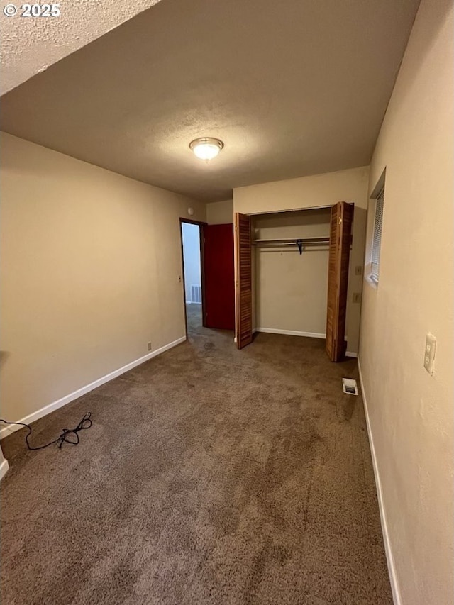 unfurnished bedroom with dark carpet, a textured ceiling, and a closet