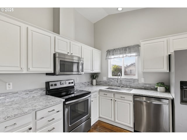 kitchen featuring a sink, appliances with stainless steel finishes, white cabinetry, and lofted ceiling