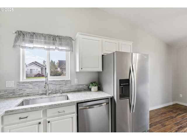 kitchen featuring white cabinets, light stone countertops, appliances with stainless steel finishes, a sink, and dark wood finished floors