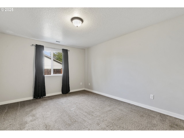 empty room with carpet floors, baseboards, a textured ceiling, and visible vents