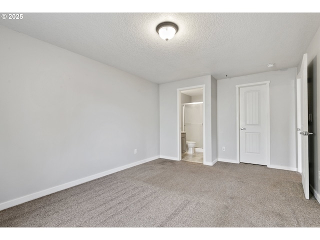 unfurnished bedroom with baseboards, carpet, ensuite bath, and a textured ceiling