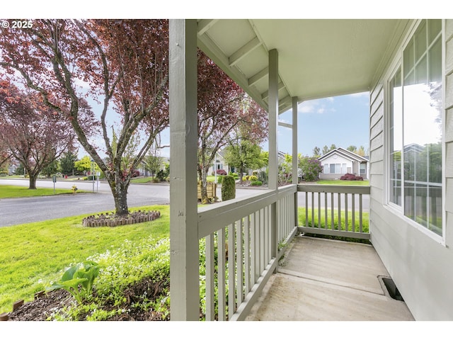 exterior space with a yard, covered porch, and a residential view