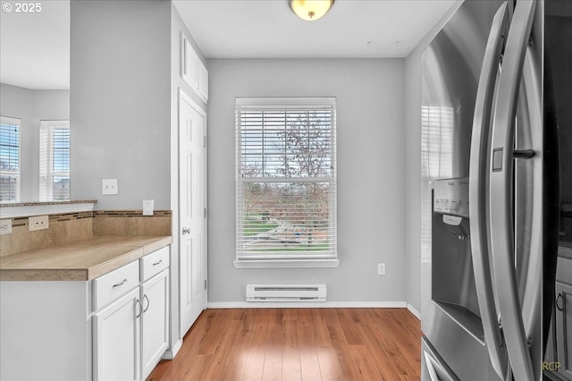 doorway to outside featuring a baseboard radiator, baseboards, and light wood finished floors