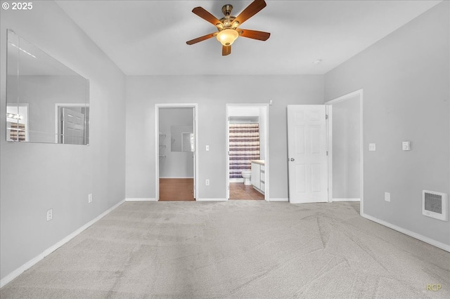 unfurnished bedroom with carpet, visible vents, baseboards, a walk in closet, and connected bathroom