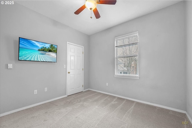 carpeted empty room with a ceiling fan and baseboards