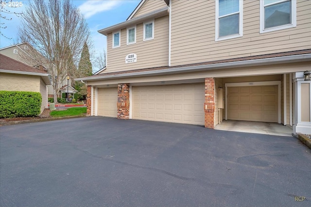 view of property exterior with aphalt driveway, brick siding, and an attached garage