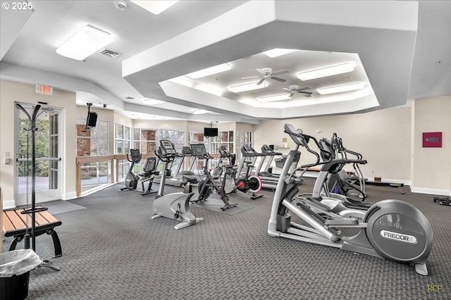 workout area with a raised ceiling, a ceiling fan, visible vents, and baseboards