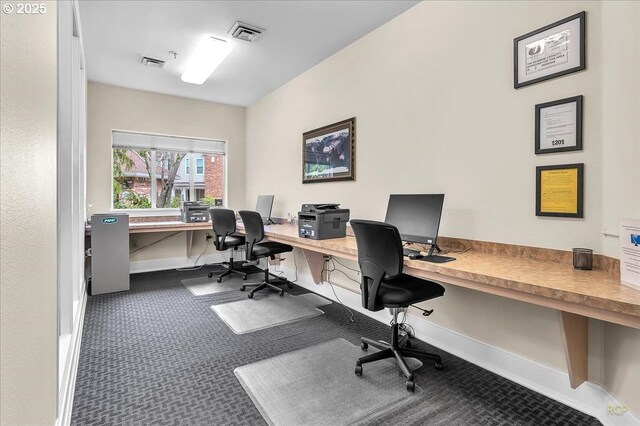 home office with built in desk, visible vents, baseboards, and carpet