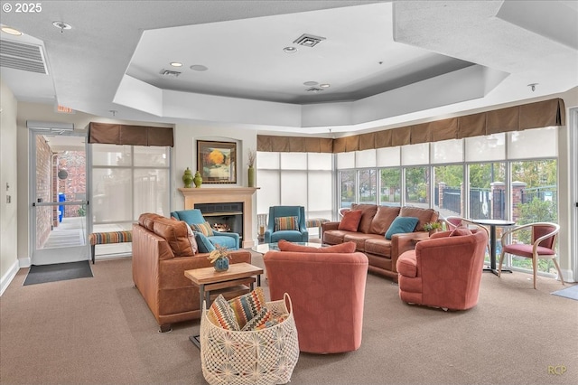 living area featuring light carpet, visible vents, a raised ceiling, and a lit fireplace