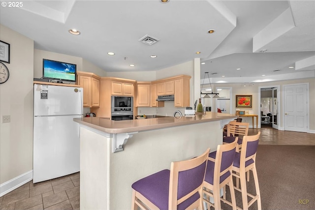 kitchen featuring oven, black microwave, under cabinet range hood, recessed lighting, and freestanding refrigerator