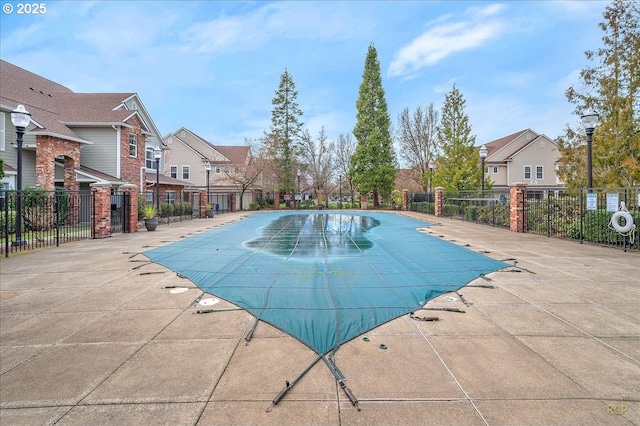 community pool with a patio area, a residential view, and fence