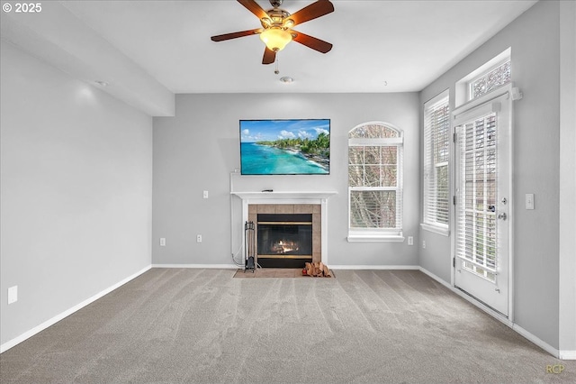 unfurnished living room featuring ceiling fan, a fireplace, baseboards, and carpet